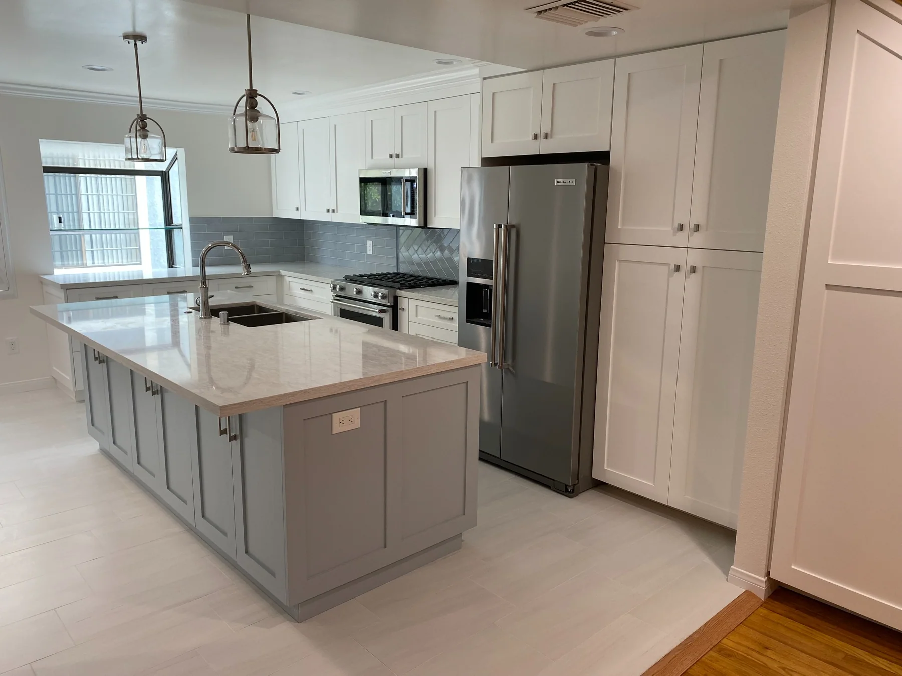 Bright renovated kitchen with gray island, white cabinets and pendant lighting
