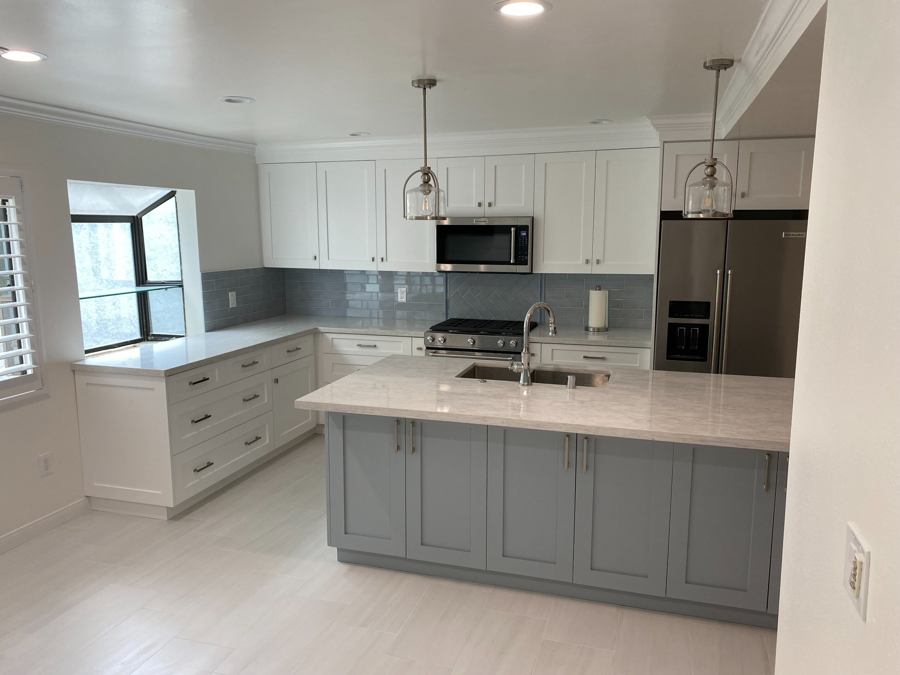 Renovated kitchen with pale gray island cabinetry and white counters